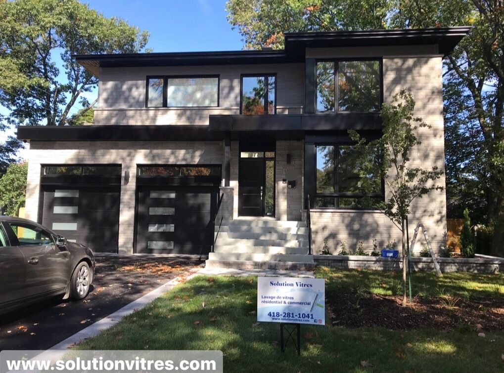 Maison moderne à deux étages avec garage double et panneau immobilier en façade