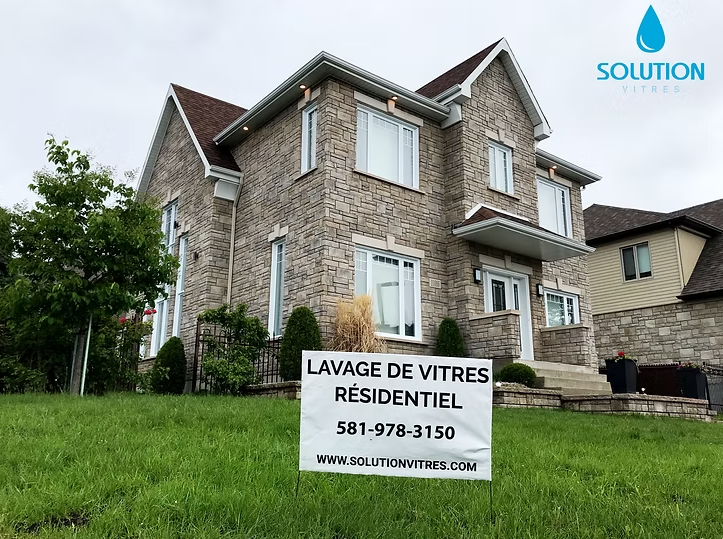 Maison en pierre avec un panneau sur la pelouse indiquant « Lavage de vitres résidentiel » et « 581-978-3150 »