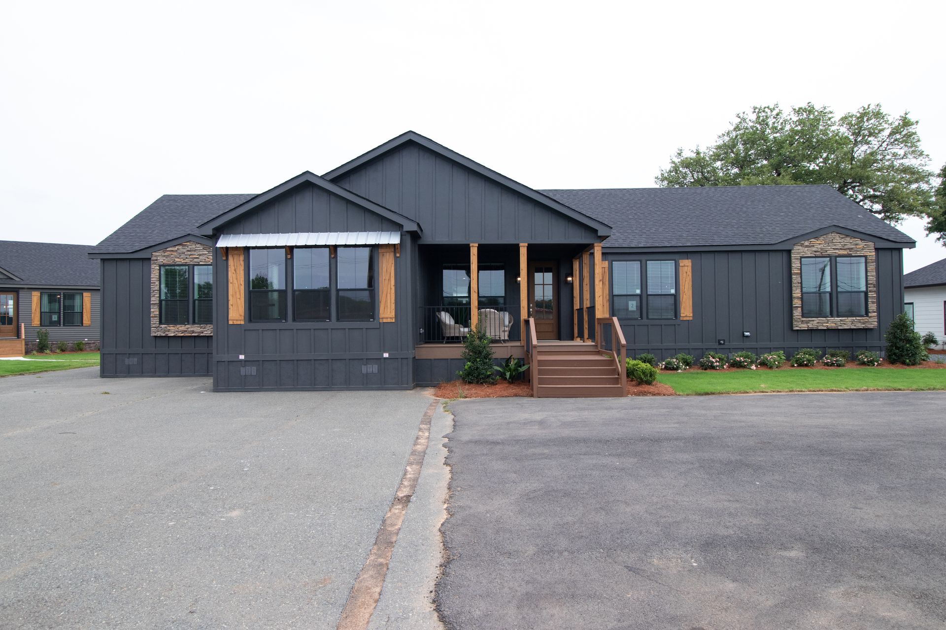 Dark gray single-story house with a central porch and gravel driveway in front