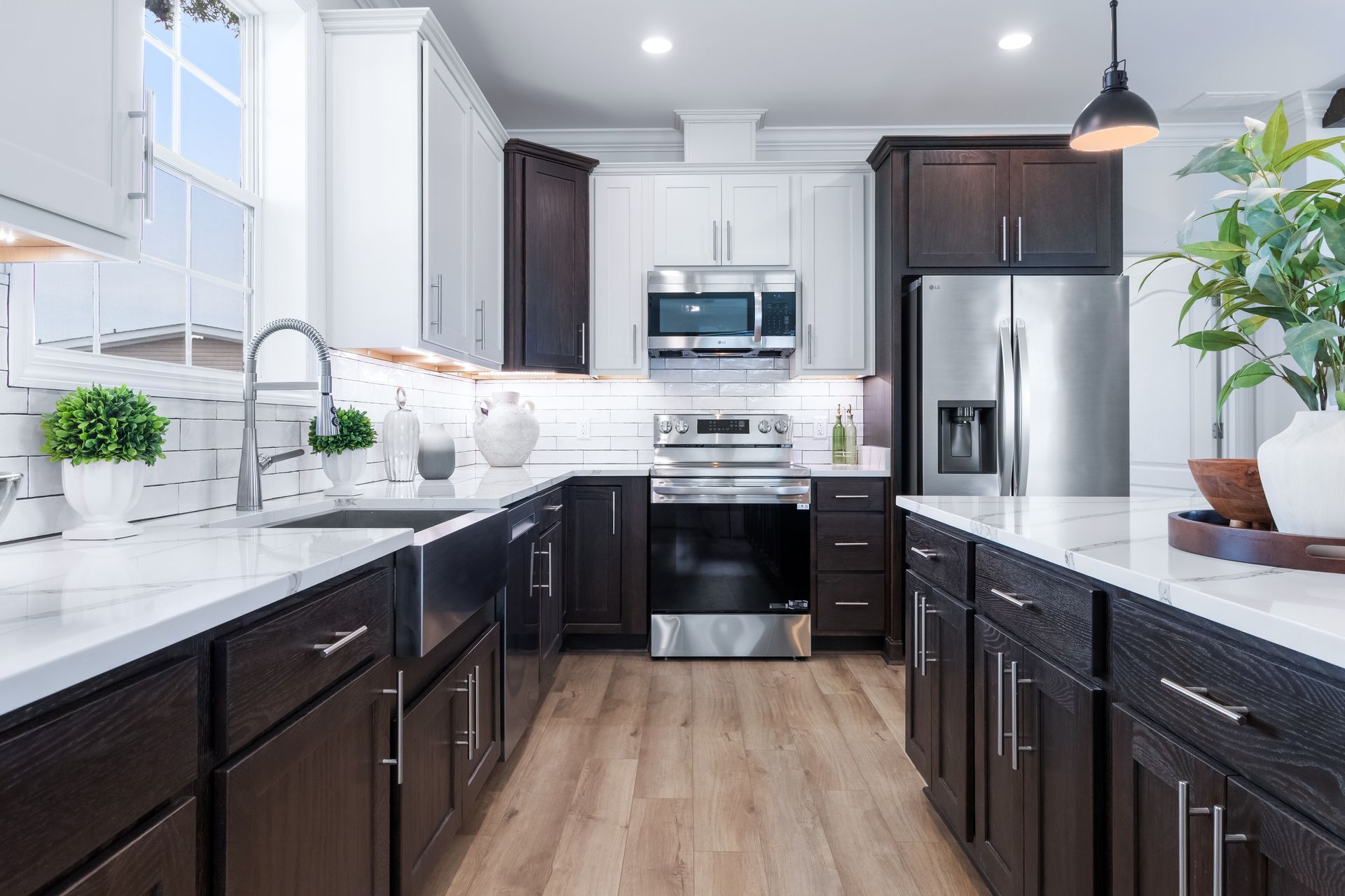 Modern kitchen with dark cabinets, white countertops, stainless steel appliances, and wood flooring