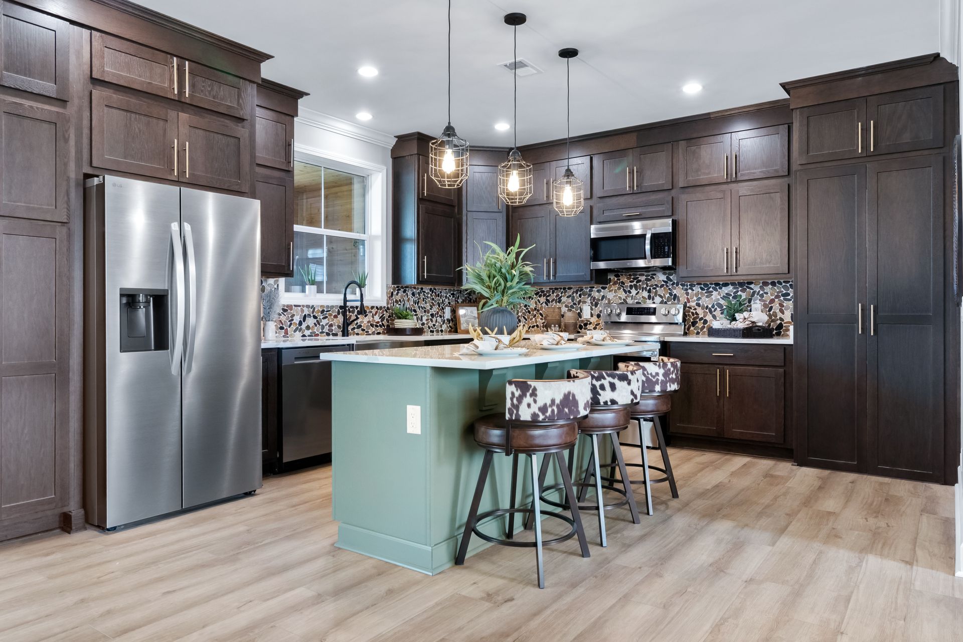 Modern kitchen with dark cabinets, stainless steel appliances, and a light green island with stools