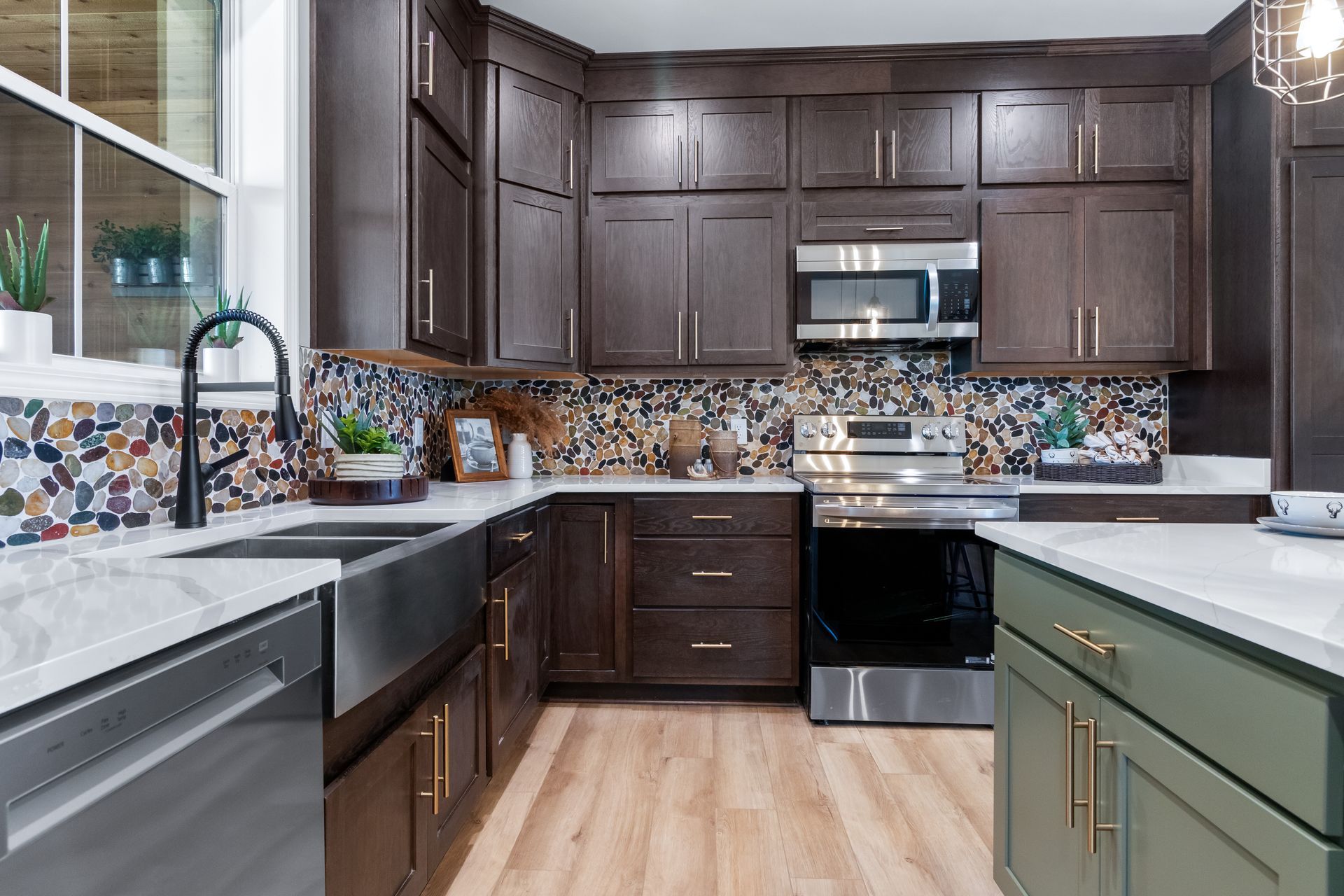 Modern kitchen with dark cabinets, colorful tile backsplash, stainless appliances, and light wood floors