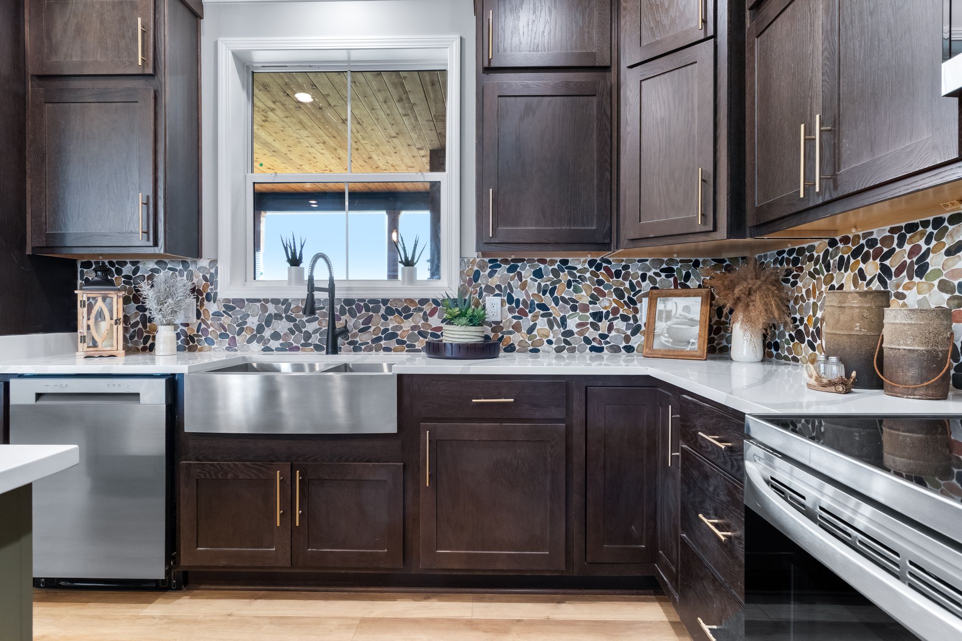 Modern kitchen with dark cabinets, stainless steel appliances, mosaic backsplash, and window above the sink