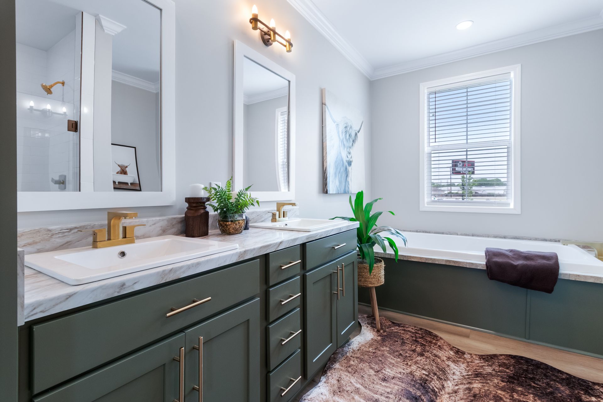 Modern bathroom with double vanity, large mirror, white walls, window seat, and potted plant.