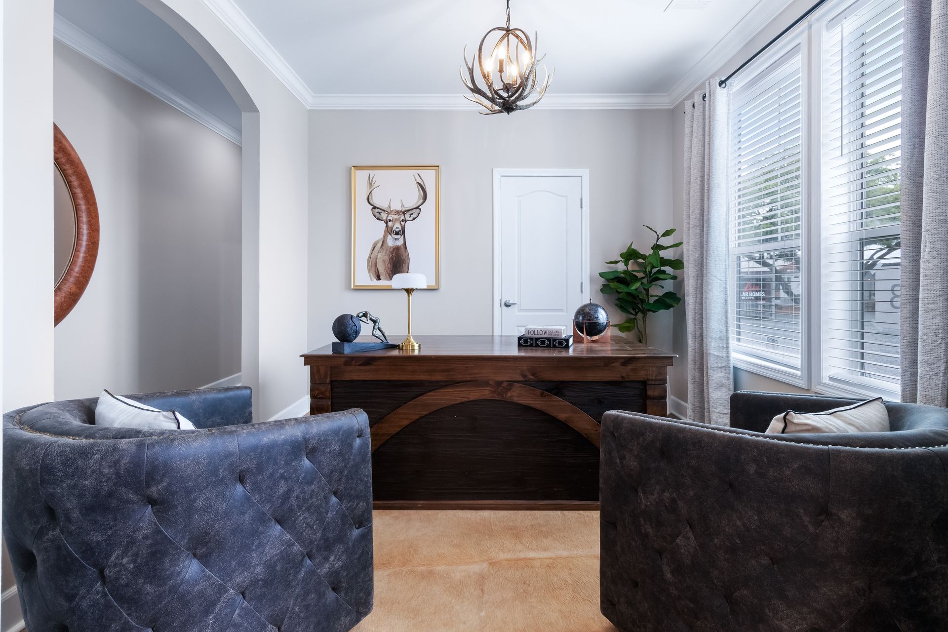 Bright home office with wooden desk, gray chairs, and large windows with blinds.