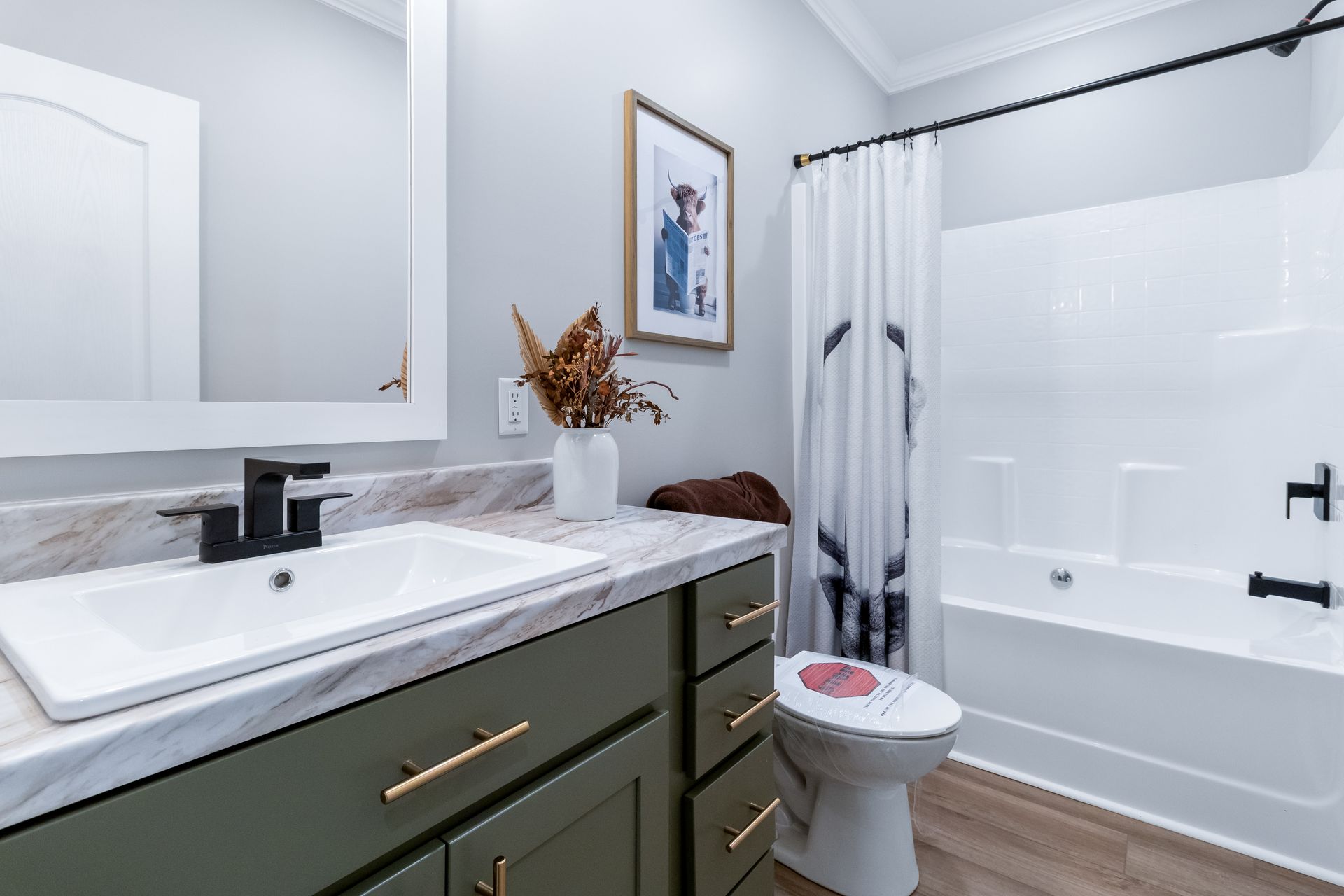 Bright modern bathroom with green vanity, white sink, toilet, bathtub, and mirror