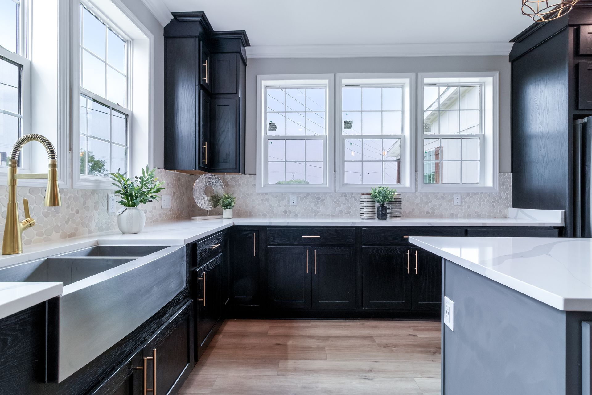Bright modern kitchen with black cabinets, white countertops, and large windows