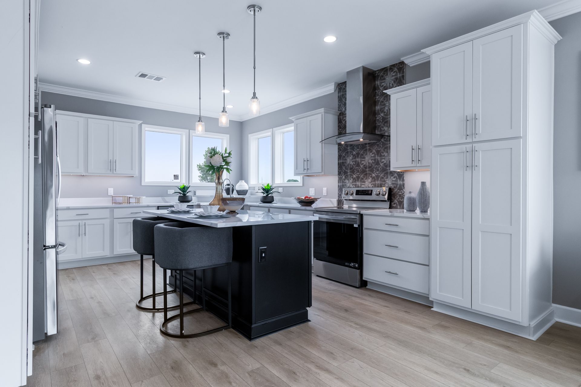 Modern white kitchen with black island, pendant lights, and gray tile backsplash