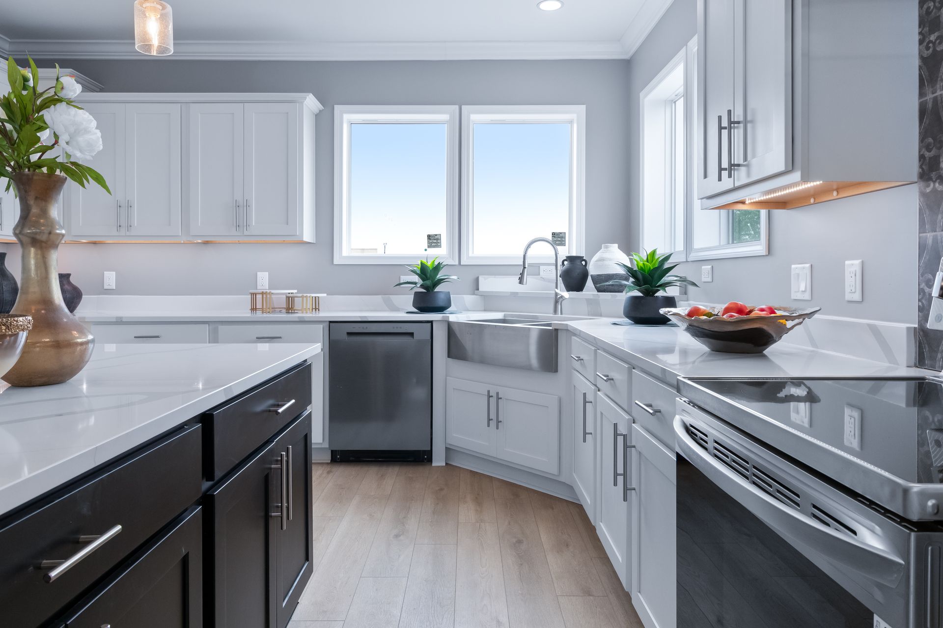 Bright modern kitchen with gray cabinets, stainless steel appliances, and a large window over the sink