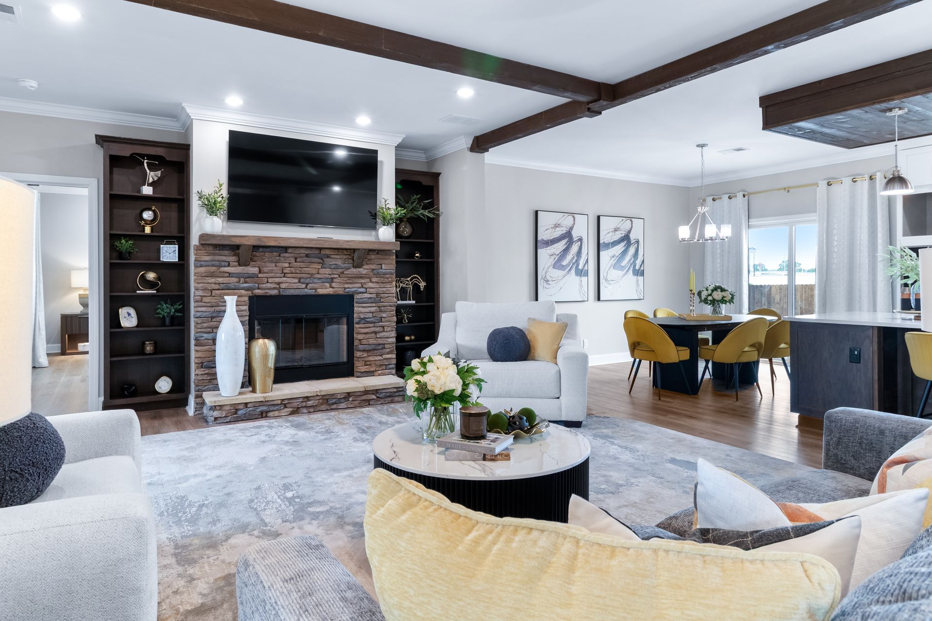 Modern living room with stone fireplace, white sofas, and dining area by bright windows