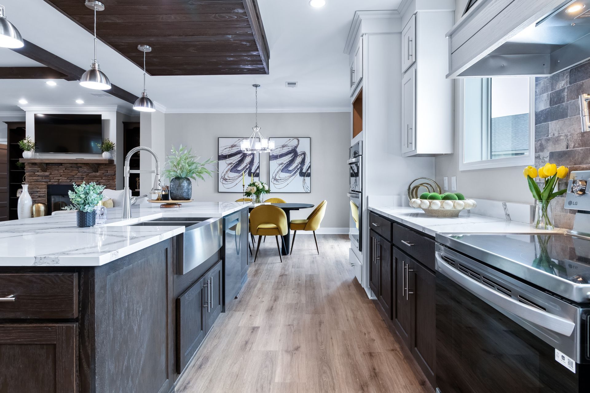 Modern kitchen with dark cabinets, white countertops, island seating, and a bright dining area.