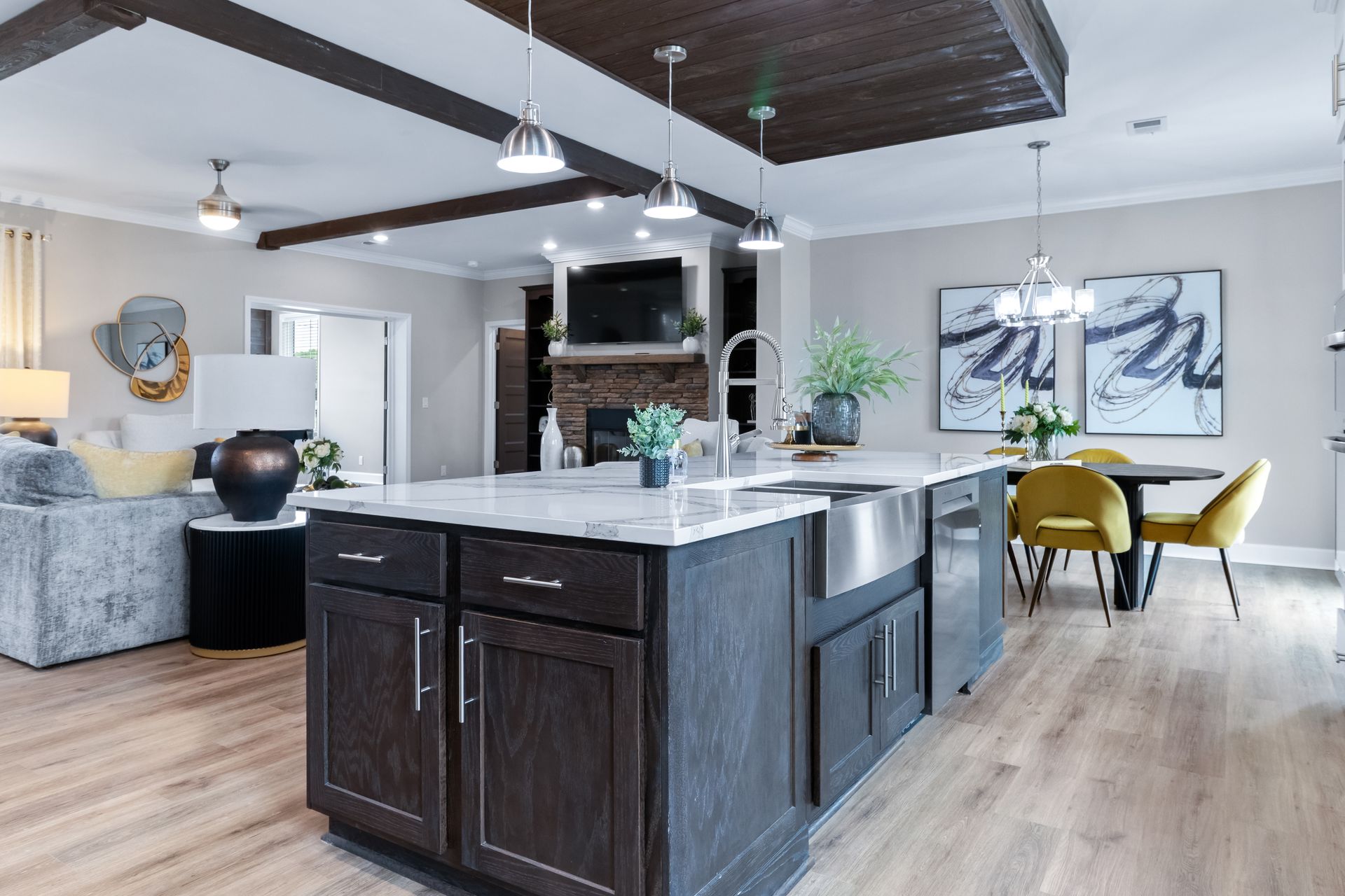 Modern open-plan kitchen and dining area with dark cabinets, white island, and yellow chairs
