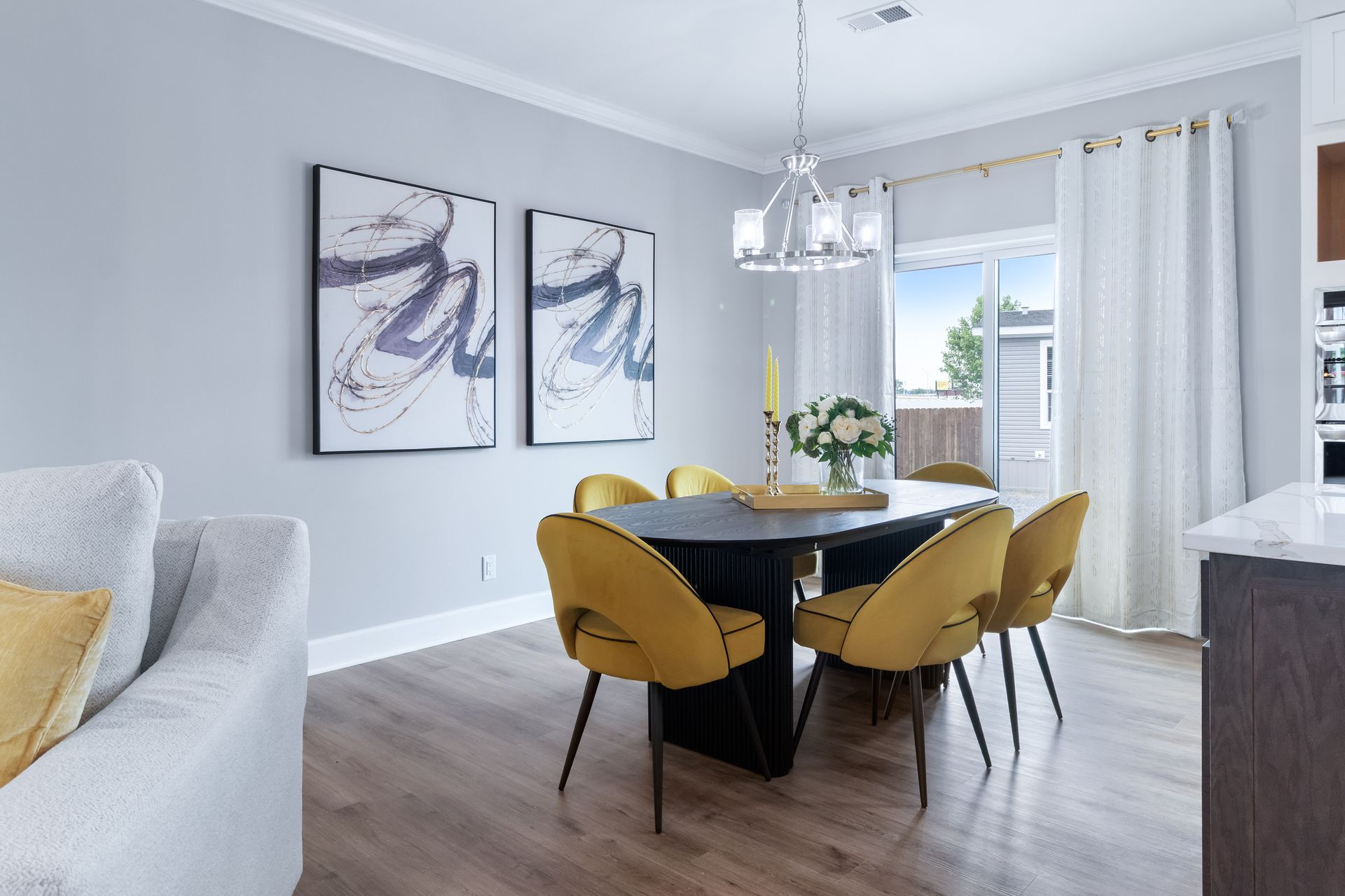Modern dining room with black table, mustard chairs, wall art, and large window with curtains