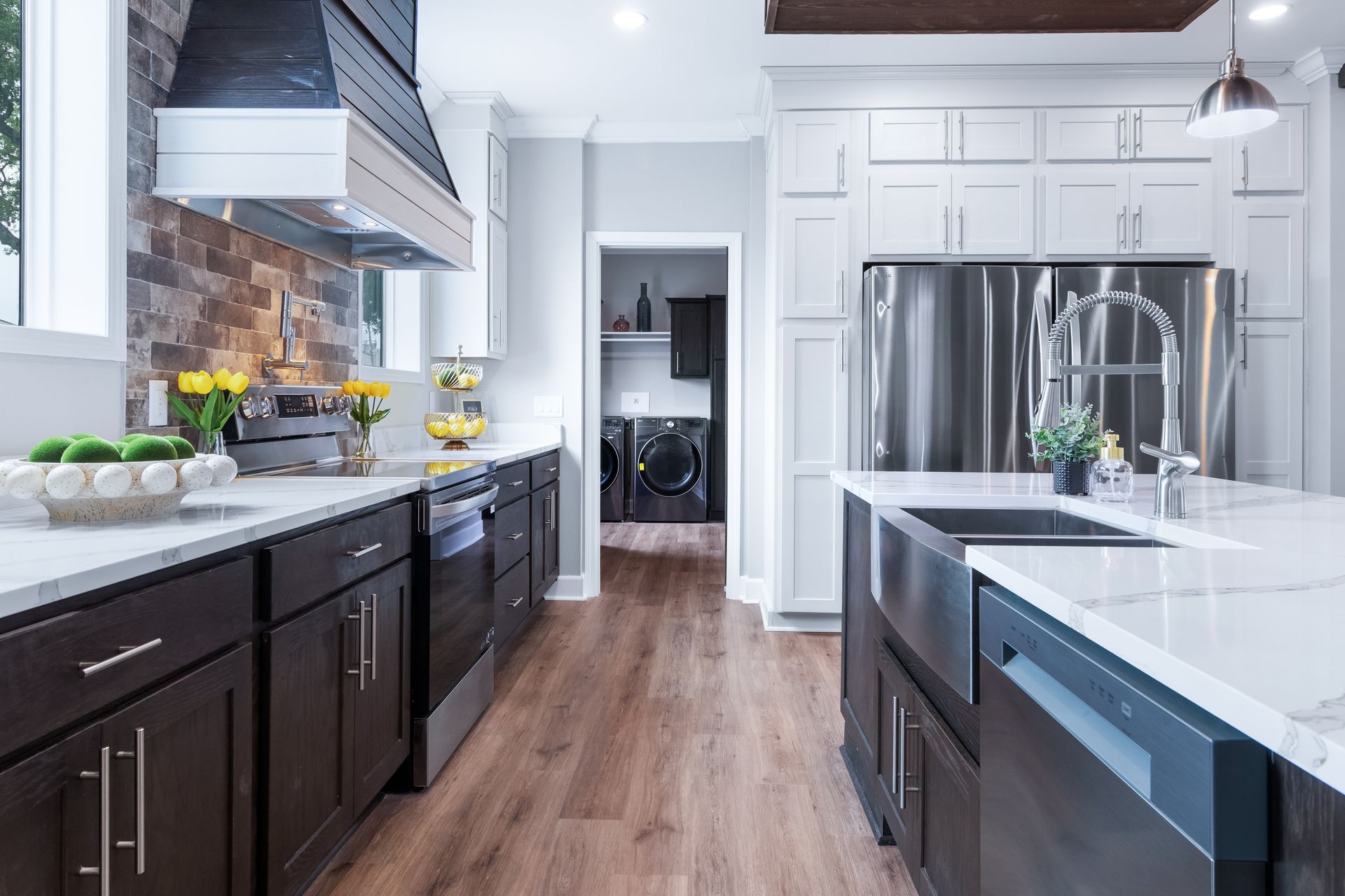 Modern kitchen with white cabinets, dark lower cabinets, stainless steel appliances, and a wood floor.