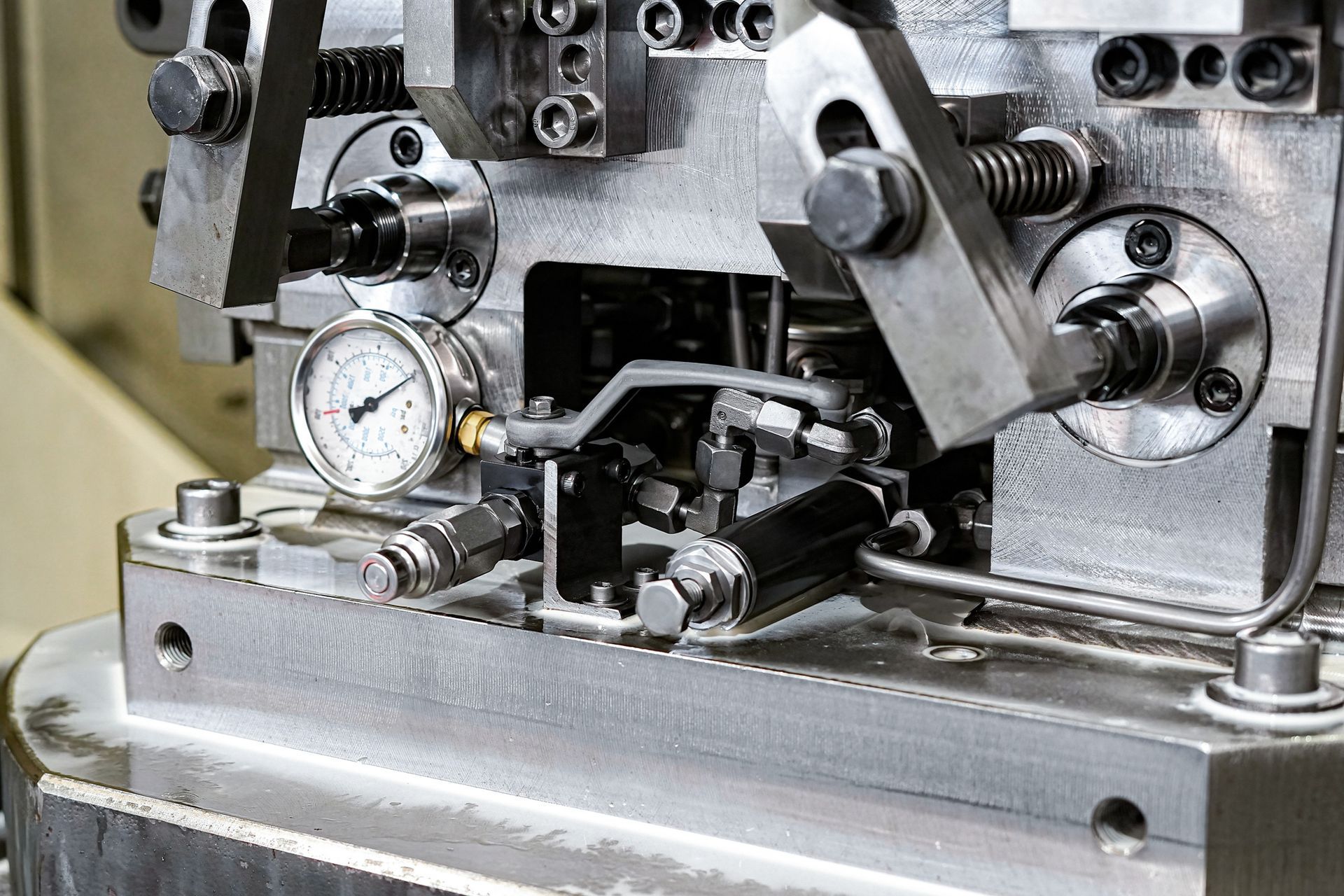 A close-up of machinery in a workshop showing detailed metal components and a pressure gauge.