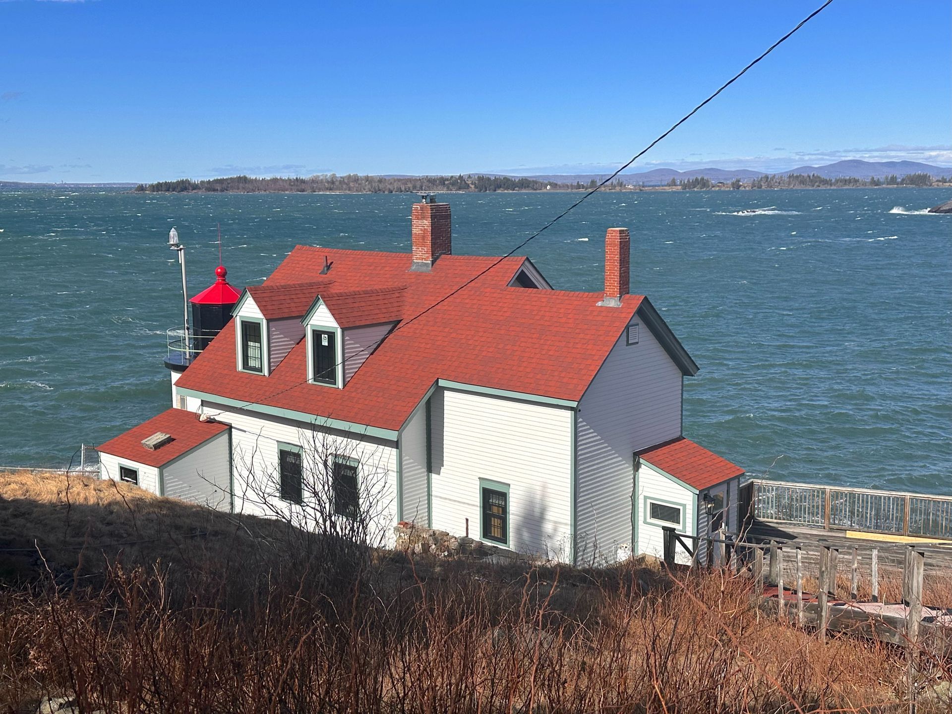 A white house with a lighthouse on top of it next to a body of water.