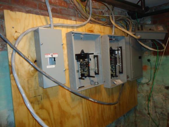 Three electrical boxes are hanging on a wooden wall.