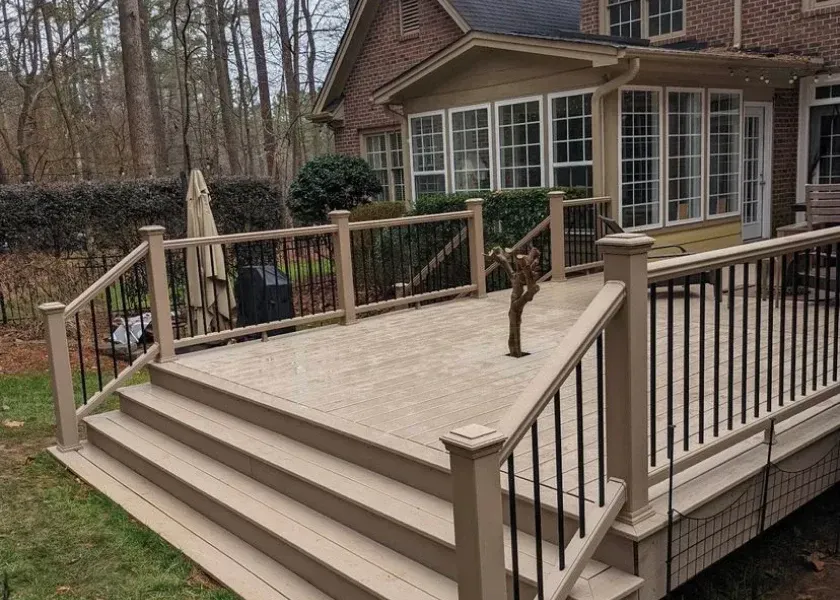 Wooden deck stairs with railing leading to a screened porch beside a wooded backyard