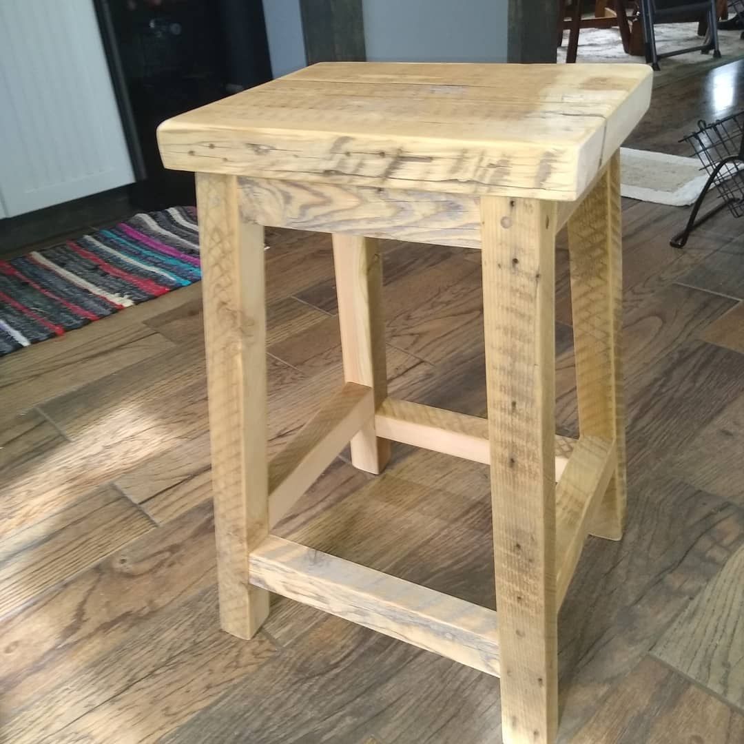 Rustic wooden stool with square top and cross braces on a hardwood floor indoors