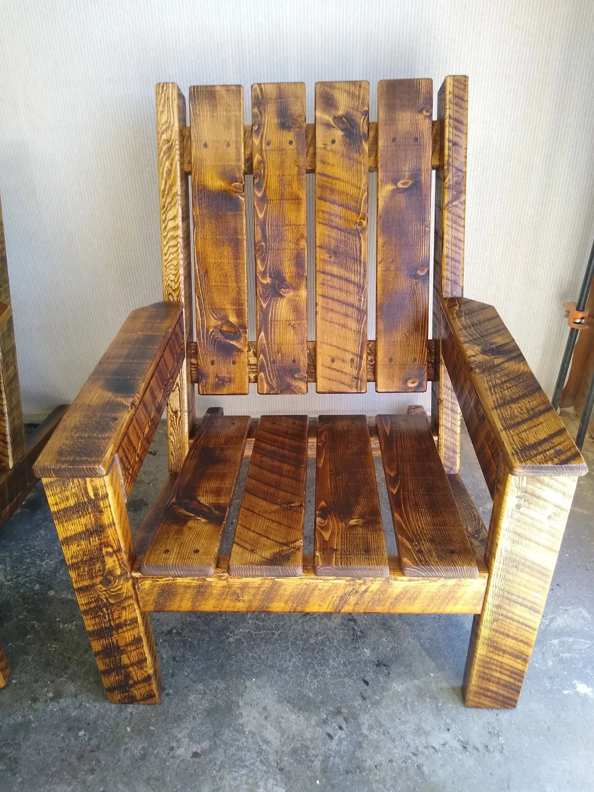 Rustic wooden armchair with a worn, weathered finish on a concrete floor