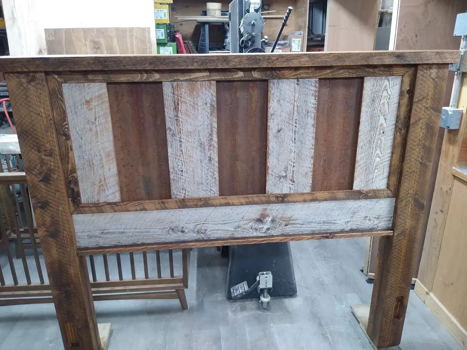 Weathered wooden gate with alternating brown and gray panels in a workshop setting