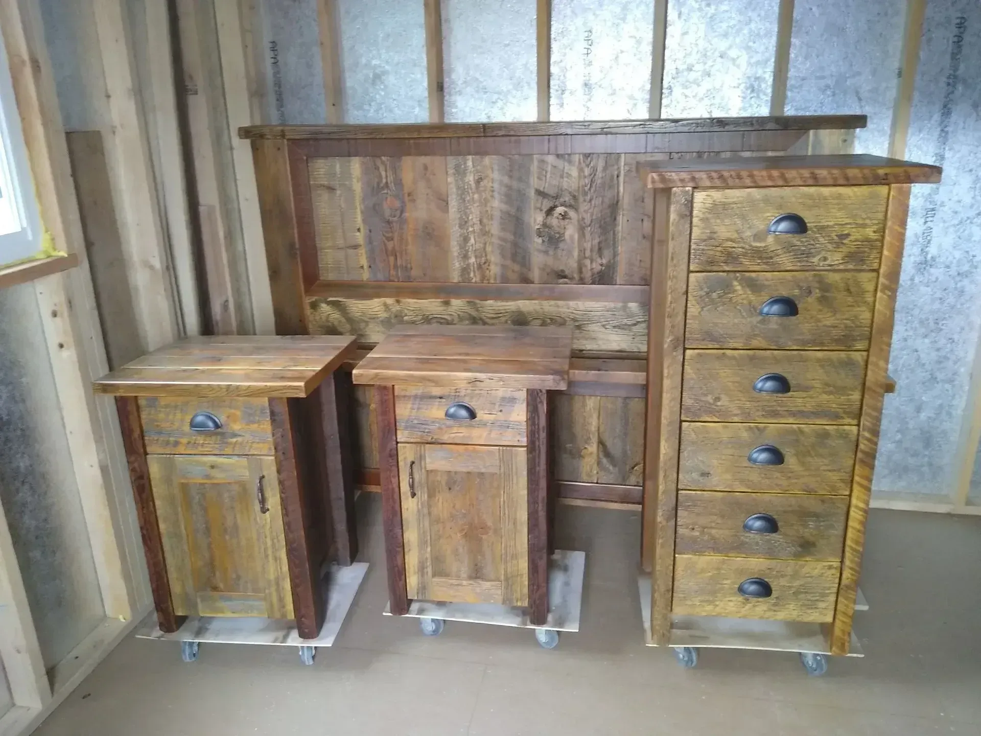 Rustic wooden bedroom furniture set with a headboard, two nightstands, and a tall dresser in a room
