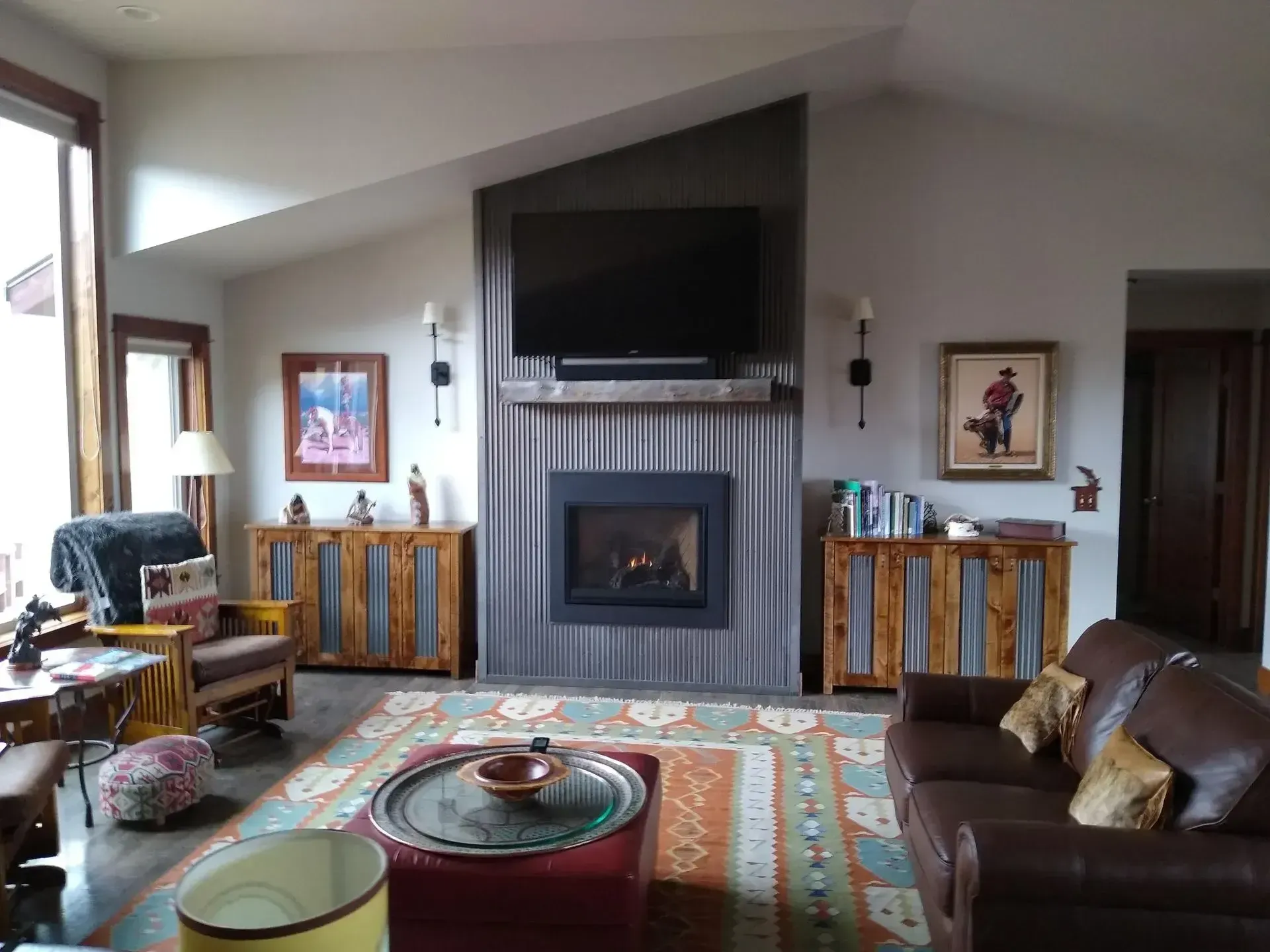 Living room with fireplace, TV, leather sofa, patterned rug, and wood side cabinets