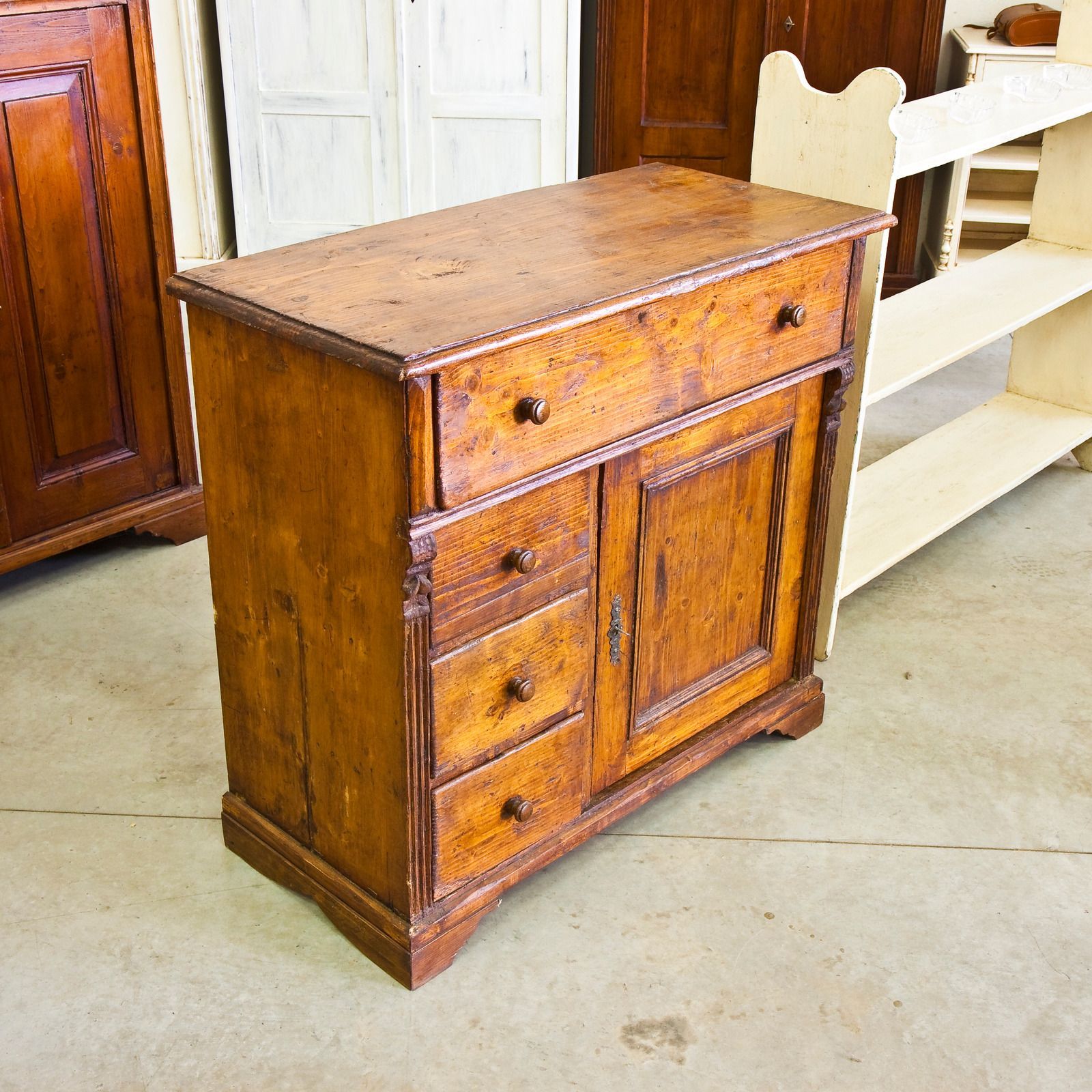 Small rustic wooden cabinet with drawers and a door, shown indoors on a concrete floor.