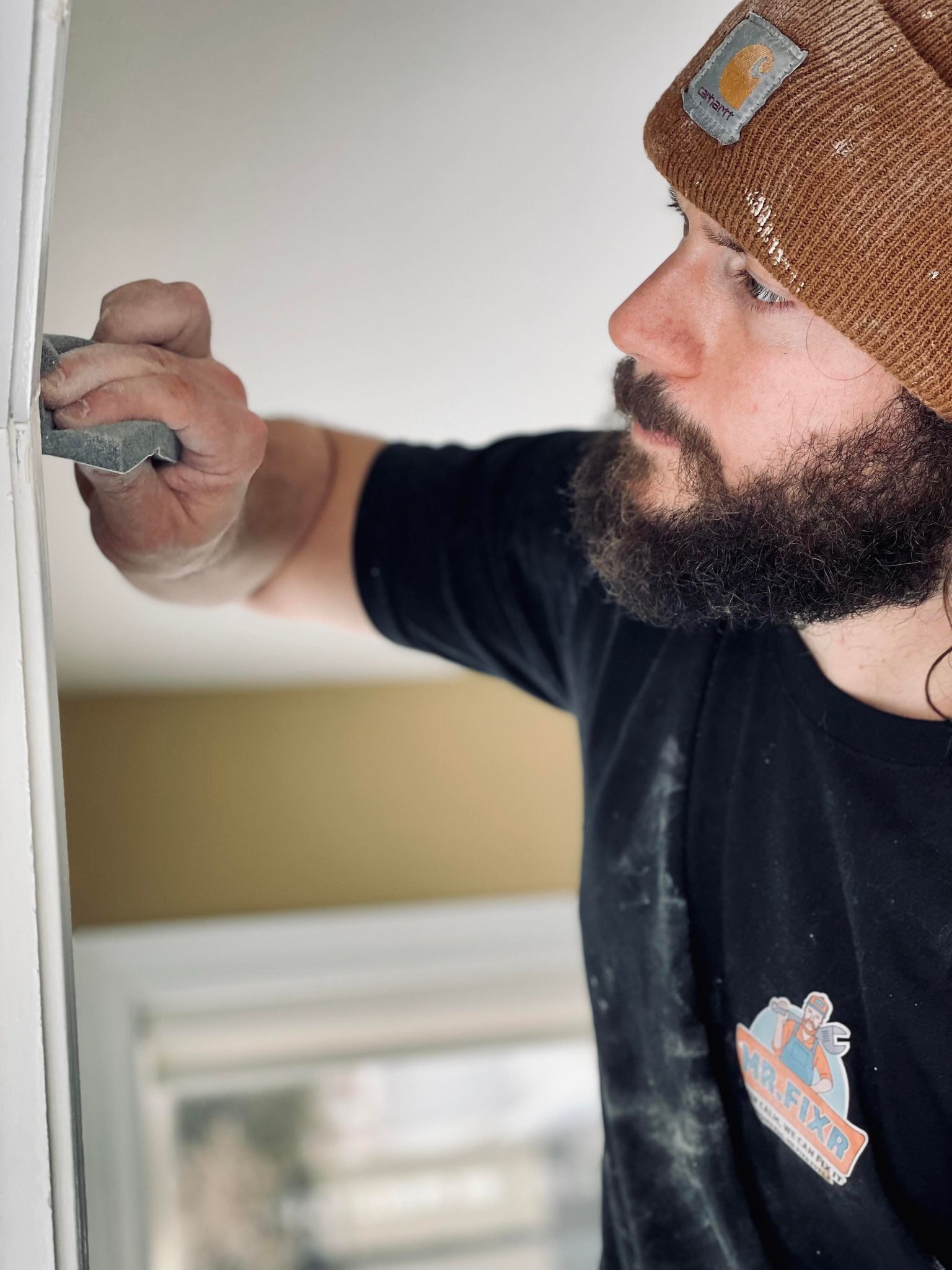 Man applying joint compound to drywall with a putty knife.