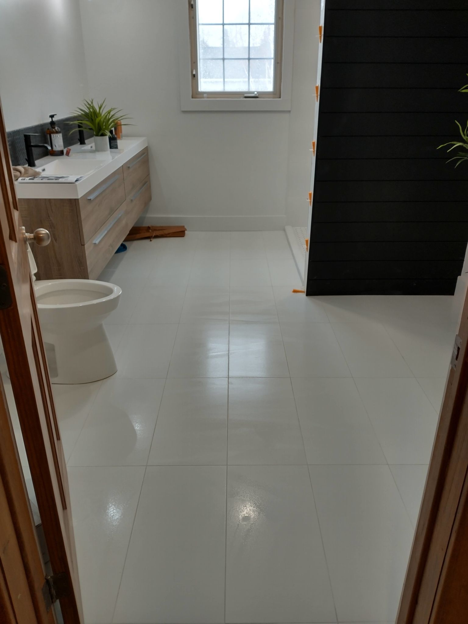 Renovated bathroom with toilet, wood vanity, white tile and window.