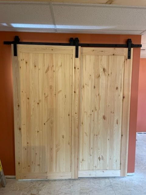 Two light wood sliding doors mounted on a black track in a room with orange walls.