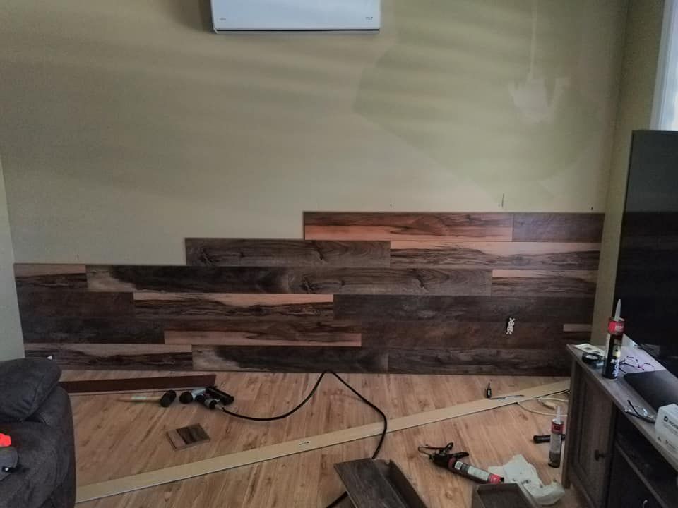 Wood flooring installation in a room, with stacked planks on the floor and construction tools.