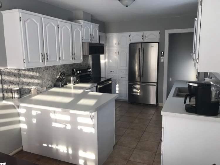 Renovated kitchen with white cabinets, stainless steel appliances and center island.