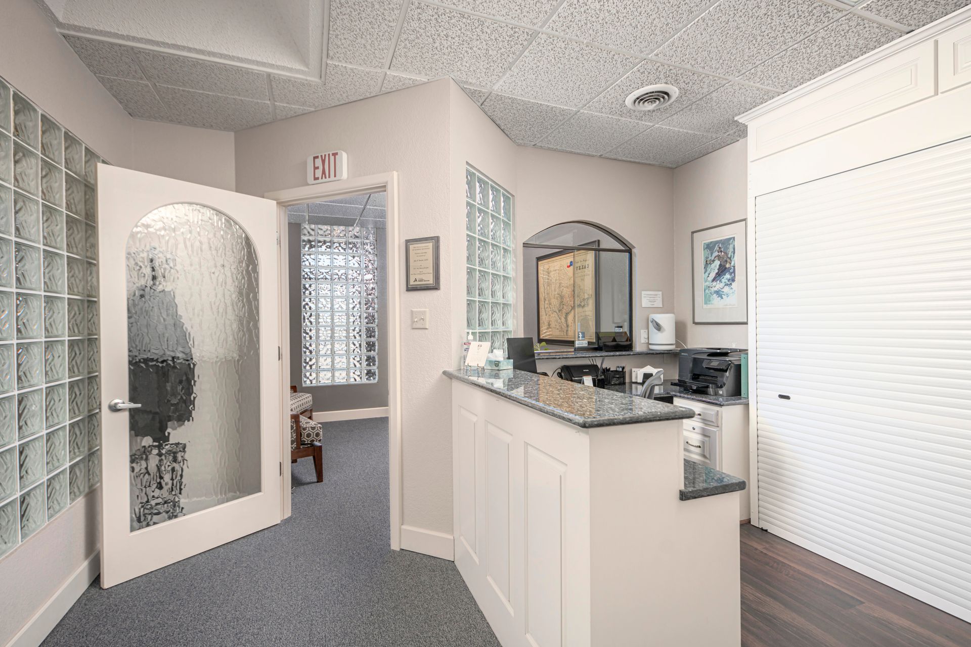 A hallway with a glass door and a counter in a room.
