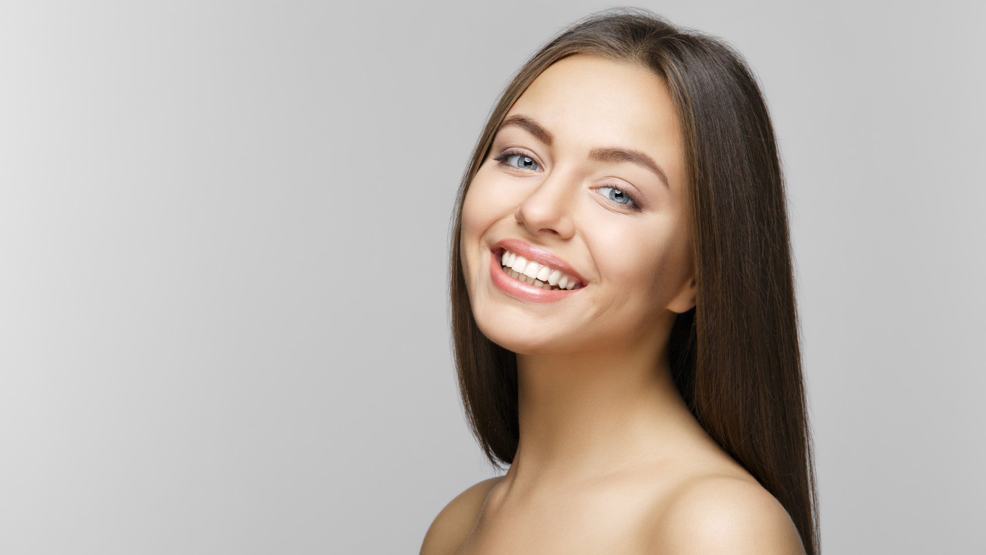 A woman with long hair is smiling and looking at the camera.