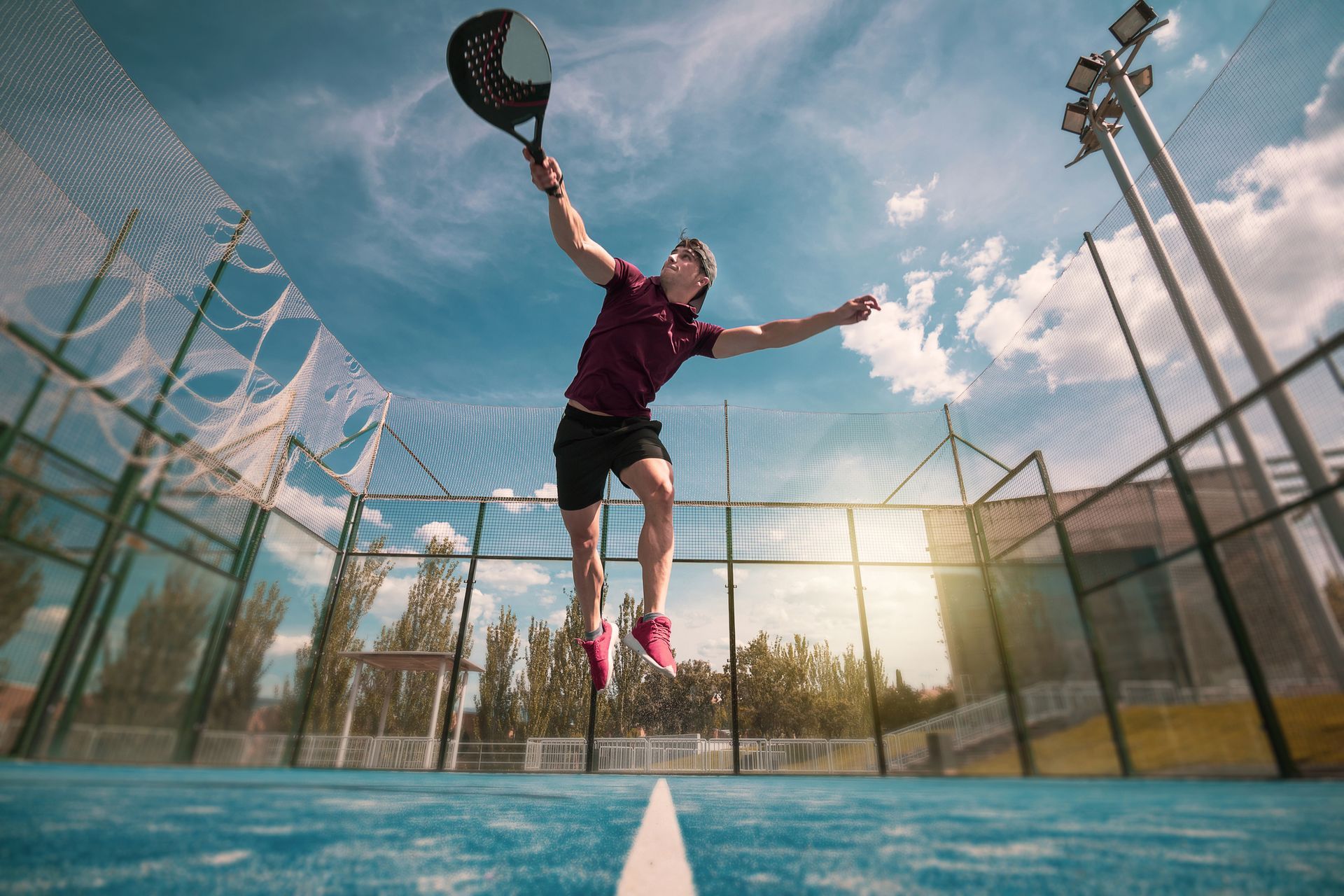 un uomo salta in aria mentre tiene in mano una racchetta da padel .