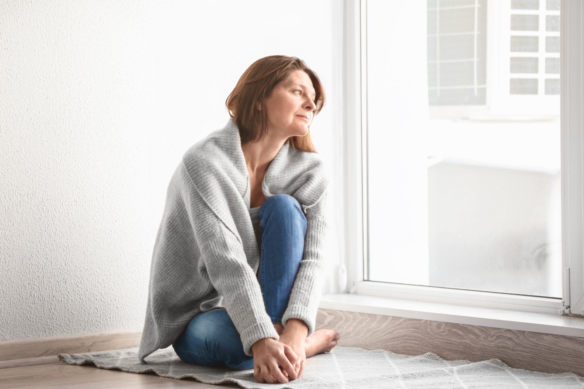 sad woman in 30s beside window