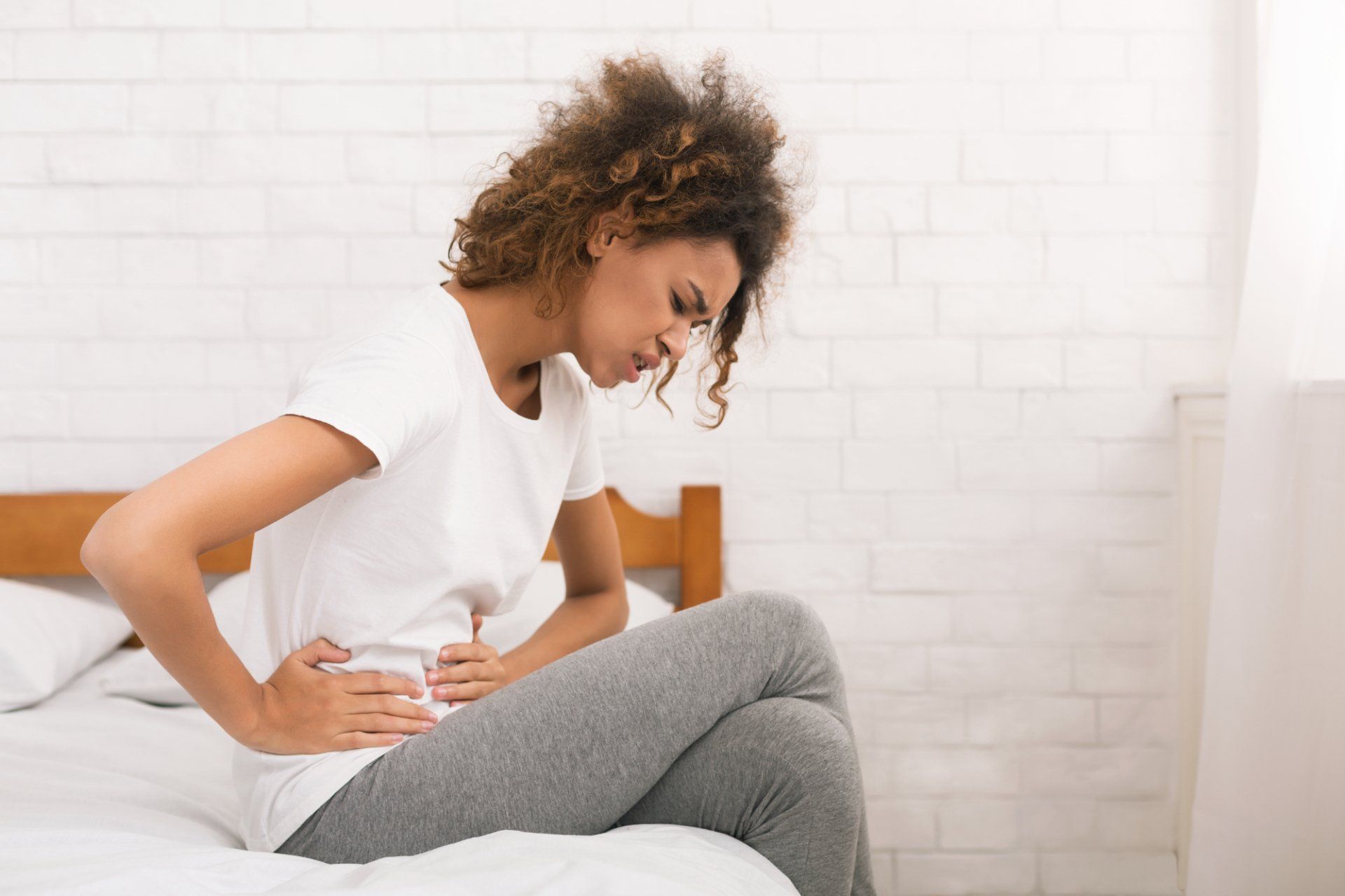 young woman holding stomach from pelvic pain