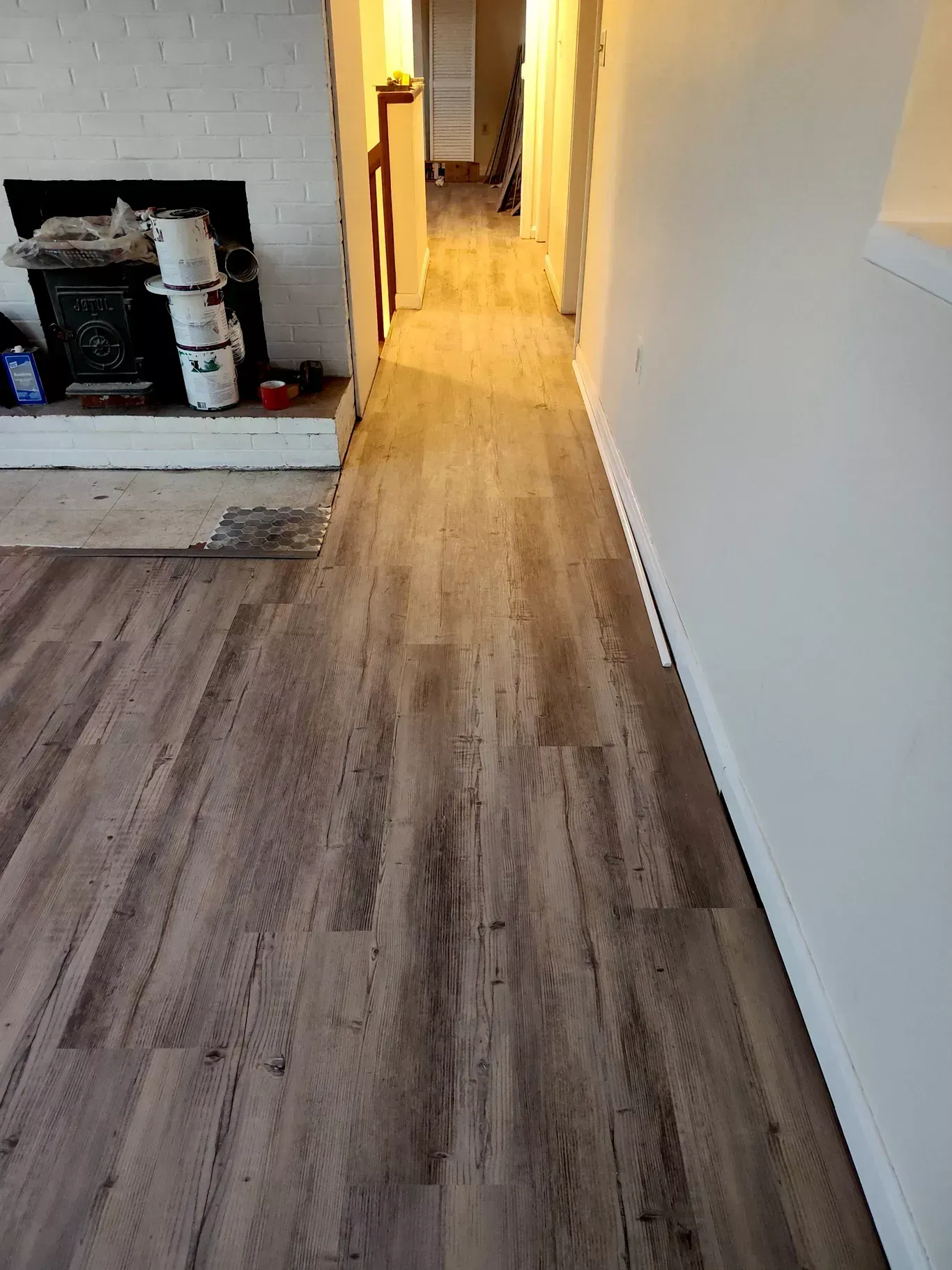 Long hallway with wood-look flooring, white walls, and a fireplace alcove on the left.