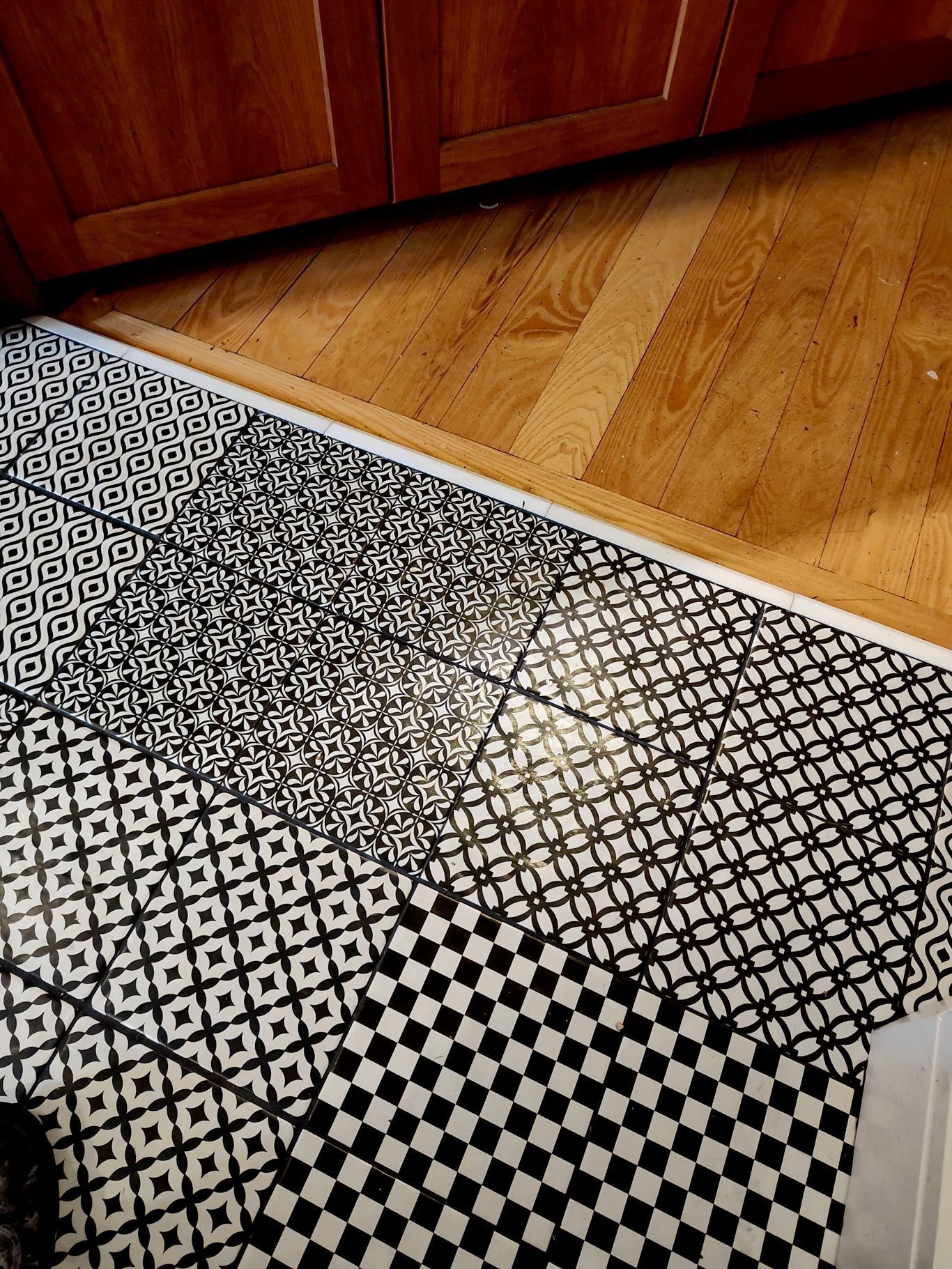 A hand installing light-colored wood laminate flooring with a rubber mallet and utility knife nearby.