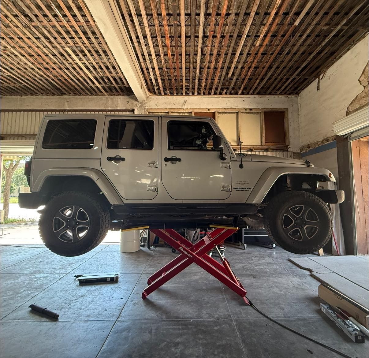 A white jeep is sitting on a lift in a garage