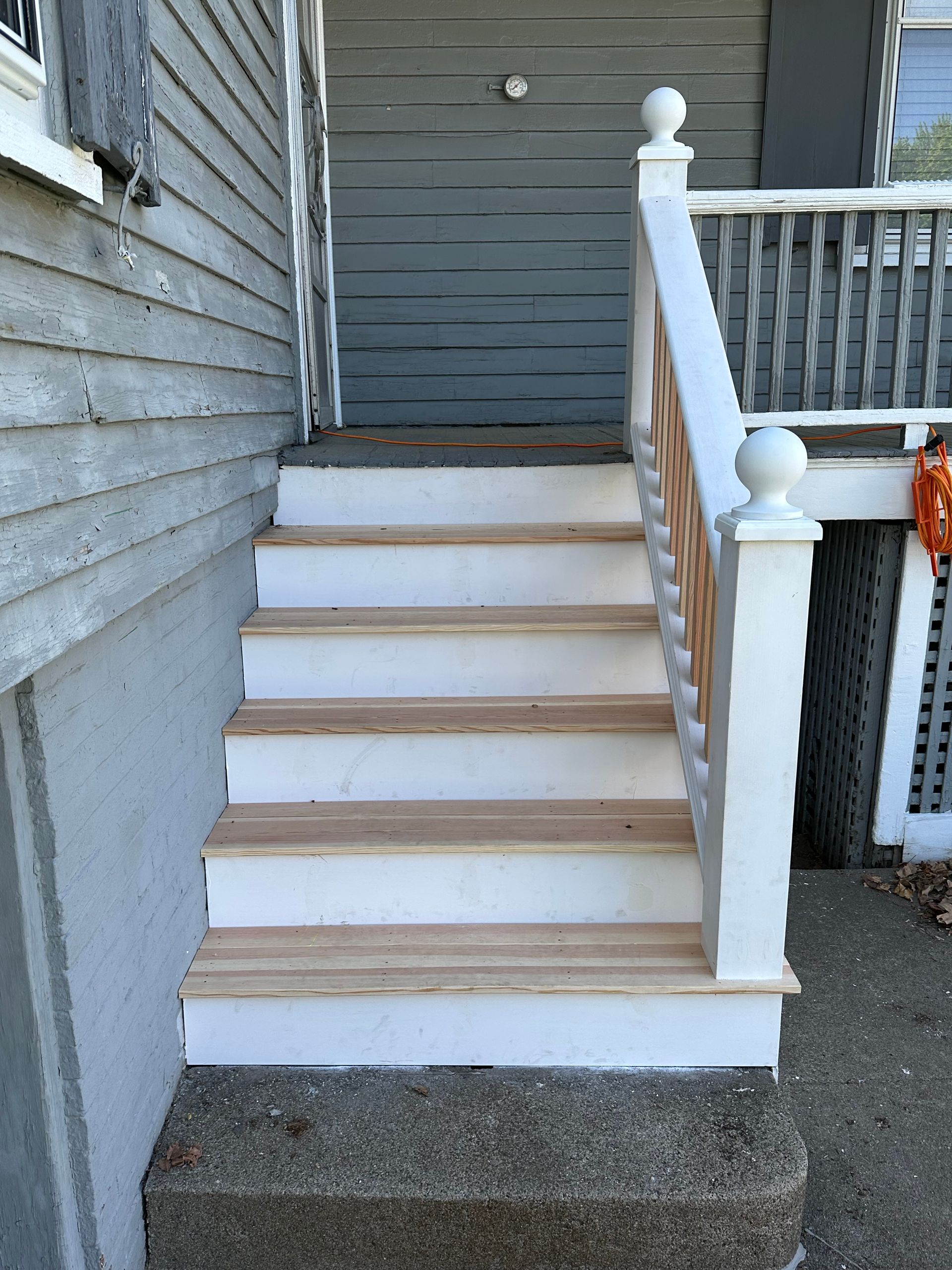 White front steps with a wooden railing leading up to a house entrance