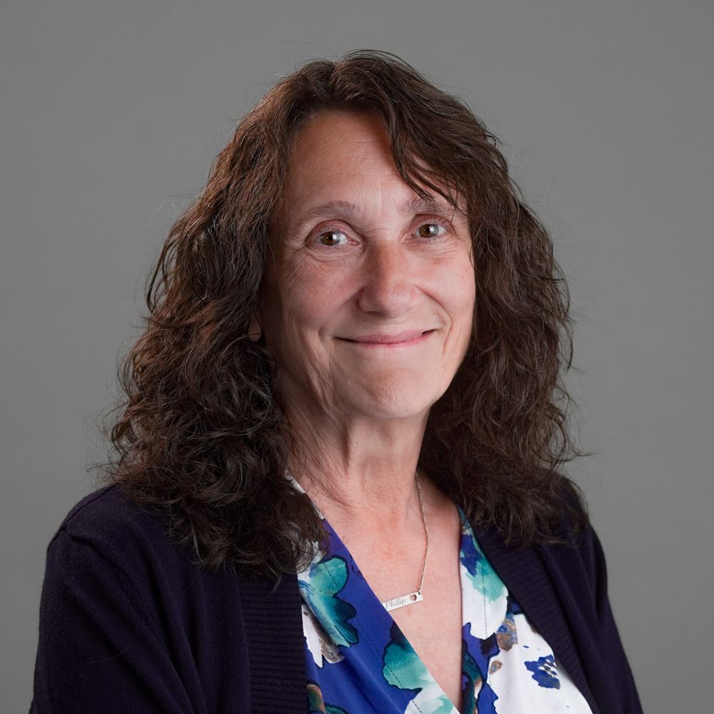 A woman in a red shirt is smiling for the camera.