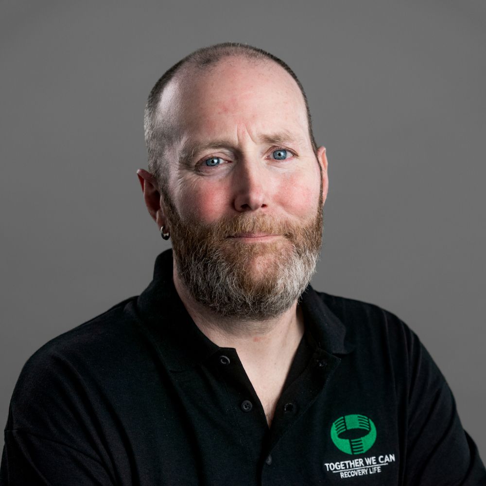 A bald man with a beard wearing a black polo shirt