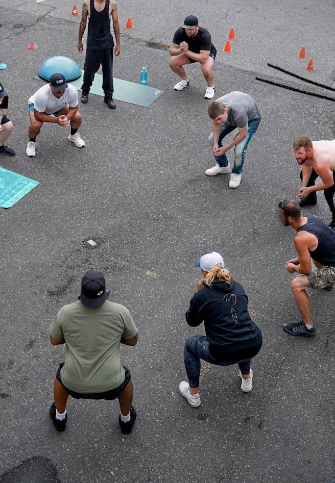 A group of people are squatting on the ground in a circle.