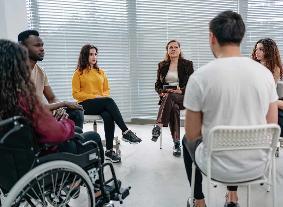 A group of people in wheelchairs are sitting in a circle.