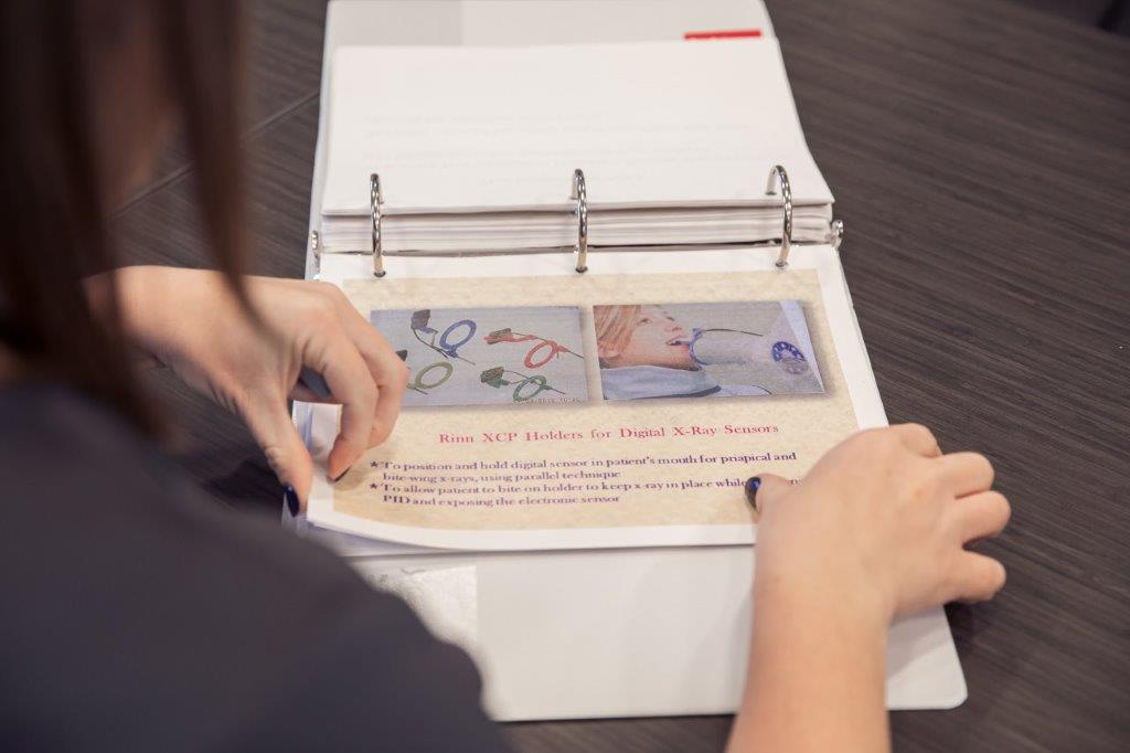 Woman flips through a binder containing images and handwritten notes.