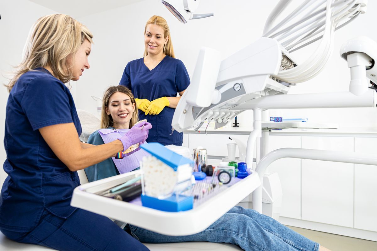 Dentist and two assistants smiling beside a patient in a bright dental clinic
