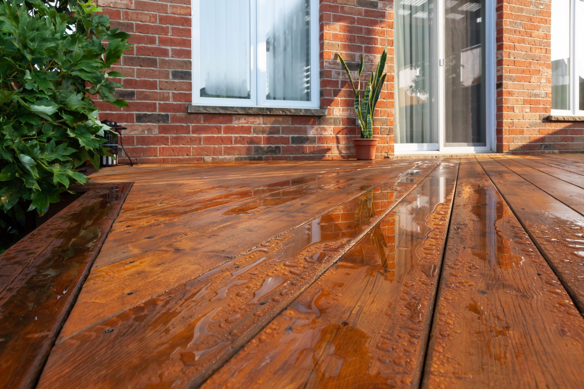 A wooden deck is sitting in front of a brick house.