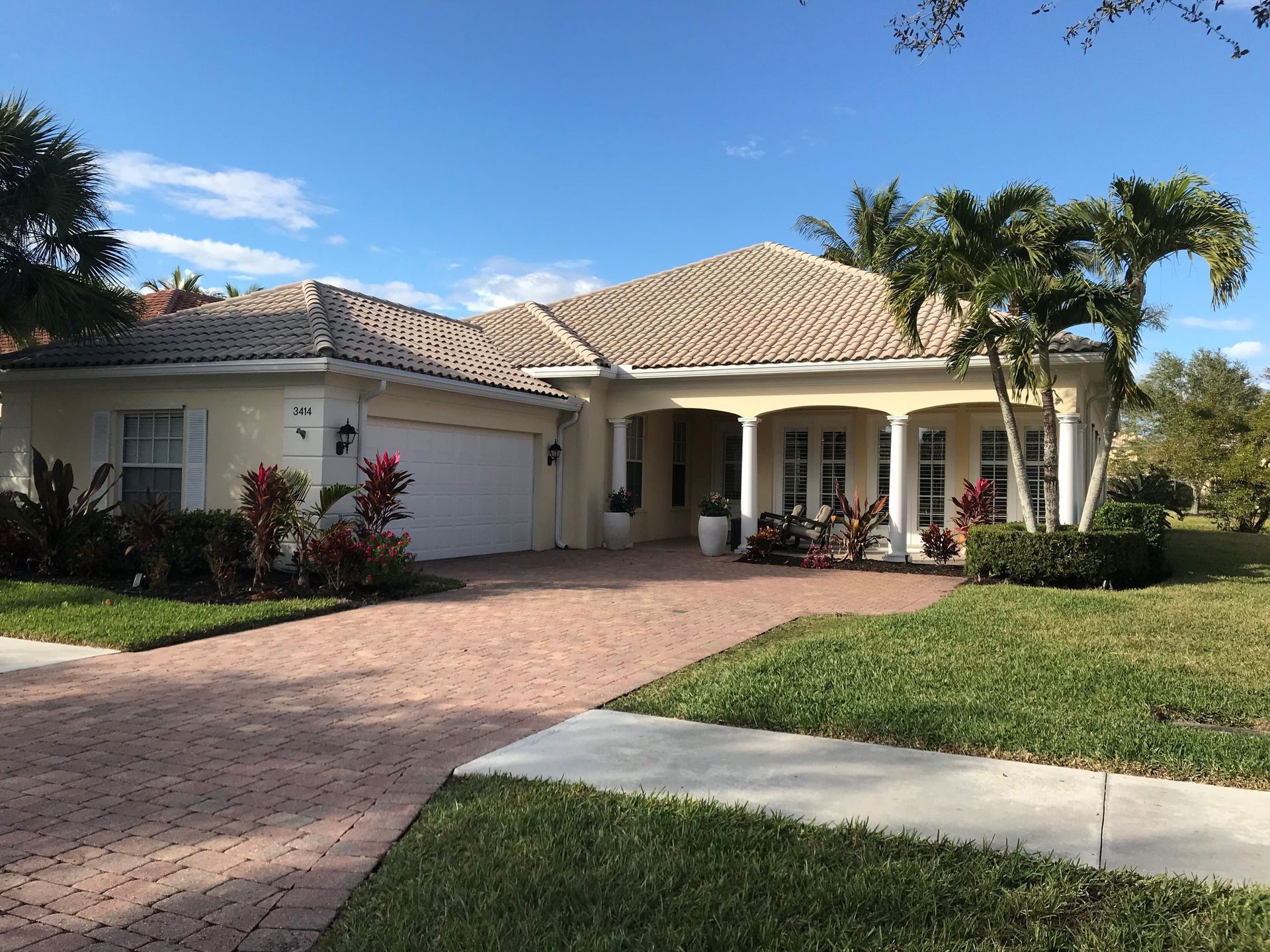 A house with a brick driveway and a large garage